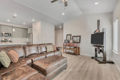 Living area with light wood-style floors, vaulted ceiling, recessed lighting, and ceiling fan