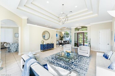 Living room with a tray ceiling, light tile patterned floors, ornamental molding, and an inviting chandelier