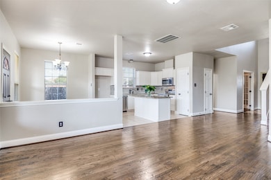 Kitchen featuring white cabinetry, a center island, backsplash, decorative light fixtures, and open floor plan
