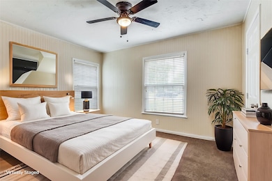 Bedroom featuring dark carpet, multiple windows, and a ceiling fan