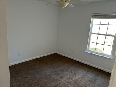 Spare room featuring dark carpet and a ceiling fan