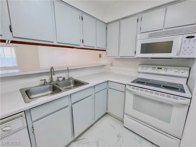 Kitchen featuring marble finish floor, a sink, white appliances, and light countertops