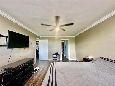 Bedroom with crown molding, dark wood-type floorin