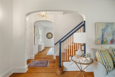 Foyer featuring arched walkways, radiator, wood fi