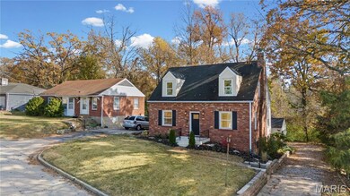 Cape cod-style house with a chimney, brick siding, and a front yard