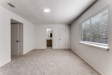 Unfurnished bedroom with light carpet, connected bathroom, and a textured ceiling