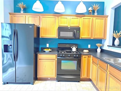 (Virtually Staged*) Kitchen with black appliances, laminate countertops, and stained cabinetry