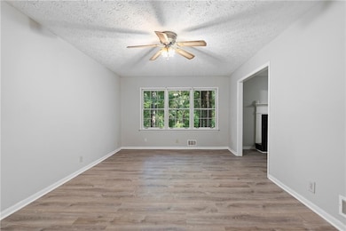 Family Room comes with a ceiling fan, a textured ceiling, and wood finished floors