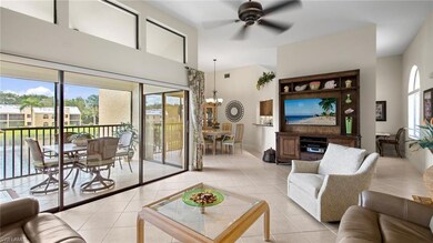 Living area with light tile patterned floors, a towering ceiling, a ceiling fan, and a chandelier