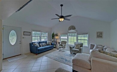 Living room with lofted ceiling, a ceiling fan, light tile patterned floors, and baseboards