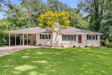 Ranch-style home featuring a front lawn, a carport, driveway, a porch, and stucco siding