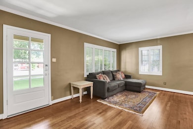 Living area featuring wood finished floors, ornamental molding, and baseboards
