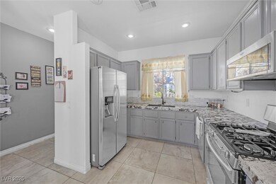 Kitchen with gray cabinets, a sink, light stone co