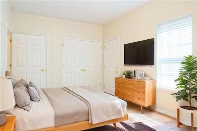 Bedroom with baseboards, light wood-style floors, and a closet