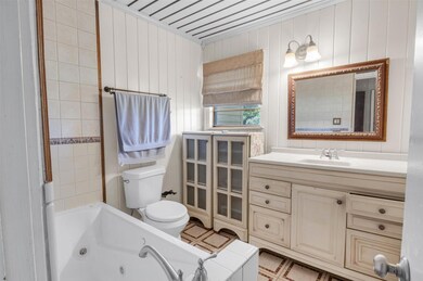 Full bathroom with toilet, a jetted tub, and vani