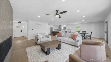 Open concept living room with large gas fireplace, dining room, and kitchen.