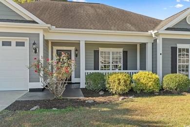 View of exterior entry with a shingled roof, a garage, covered porch, and a lawn