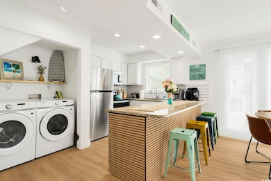 Kitchen featuring appliances with stainless steel finishes, a peninsula, light wood-style floors, white cabinetry, and recessed lighting