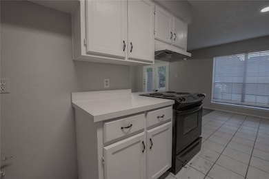 Kitchen featuring white cabinetry, electric range, light countertops, light tile patterned floors, and under cabinet range hood