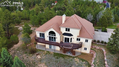 Back of house with a tiled roof, a patio, a chimney, a deck, and wooded view