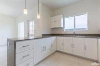 Kitchen featuring decorative light fixtures, plenty of natural light, and white cabinetry