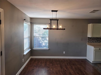 Unfurnished dining area with dark wood-style flooring and a chandelier
