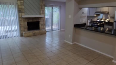 Kitchen featuring ventilation hood, stainless steel gas range oven, dark countertops, light tile patterned floors, and white cabinets