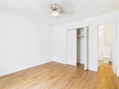 Unfurnished bedroom with light wood-style floors, a closet, and a ceiling fan