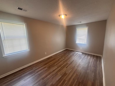 Spare room featuring dark wood-style floors, baseboards, and a textured ceiling