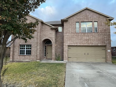 Traditional-style home featuring brick siding, concrete driveway, a front yard, and a garage