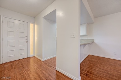 Foyer with wood finished floors and a textured cei