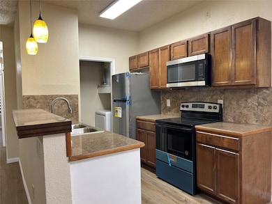 Kitchen with decorative backsplash, a textured cei