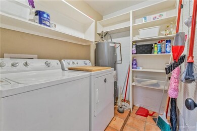 Laundry room featuring washer and dryer, water heater, and light tile patterned floors