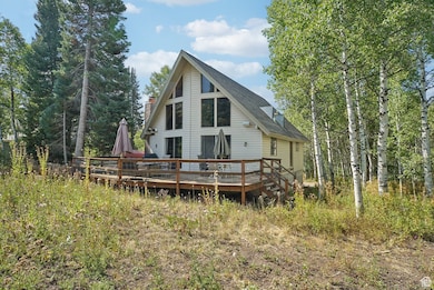 Back of house featuring a deck, a shingled roof, and a chimney