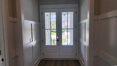 Doorway featuring french doors, a decorative wall, and dark wood-style floors