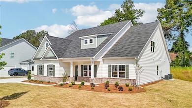 View of front facade featuring brick siding, a porch, a front yard, and roof with shingles