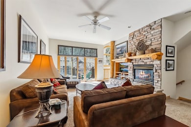 Carpeted living area featuring ceiling fan, a fire
