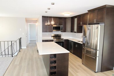 Kitchen featuring appliances with stainless steel finishes, dark brown cabinets, LVP floors, Quartz countertops, and a center island