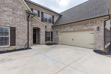 View of front of home with a garage, brick siding, driveway, and a shingled roof
