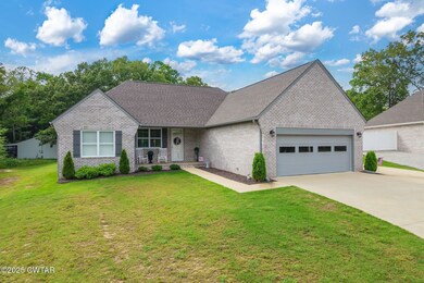 View of front of property with a garage, brick siding, concrete driveway, a porch, and a front lawn