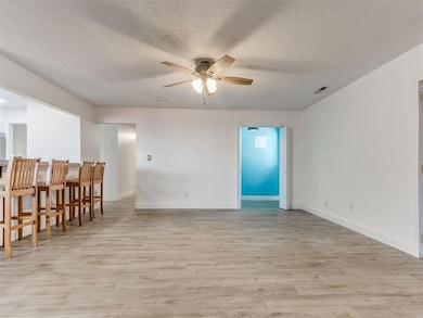 Unfurnished room with ceiling fan, light wood finished floors, and a textured ceiling
