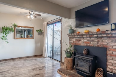 Living room featuring laminate flooring, a wood stove, and ceiling fan