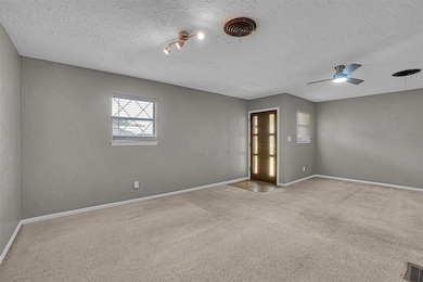 Carpeted spare room with a textured ceiling, ceiling fan, and a textured wall