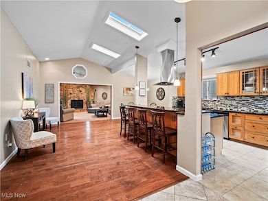 Kitchen featuring a skylight, tasteful backsplash, a breakfast bar area, glass insert cabinets, and open floor plan