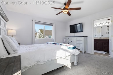 Bedroom featuring light carpet, ensuite bathroom, and ceiling fan