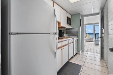 Kitchen featuring white cabinetry, freestanding refrigerator, light countertops, electric range, and light tile patterned floors