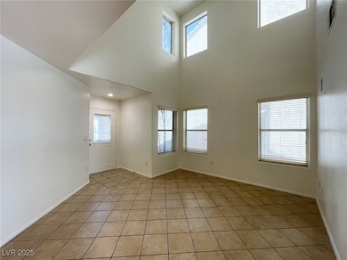 Unfurnished room featuring healthy amount of natural light, light tile patterned floors, and a high ceiling
