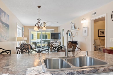 Kitchen with a sink, a textured ceiling, open floo