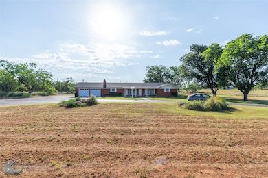 Single story home with driveway, an attached garage, and a front lawn