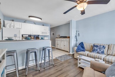 Kitchen with white appliances, a breakfast bar, li